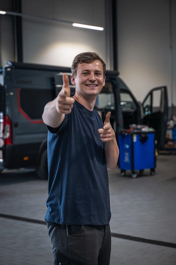 Ein junger Kfz-Mechaniker vom Freizeit-Center Albrecht steht in der Werkstatthalle vor einem Kastenwagen mit geöffneter Tür