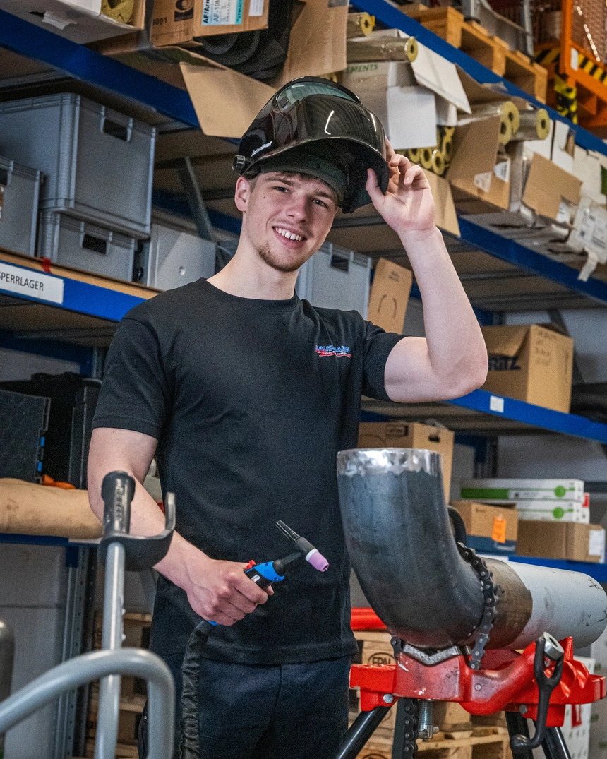 Junger Mitarbeiter mit Helm in der Werkstatt