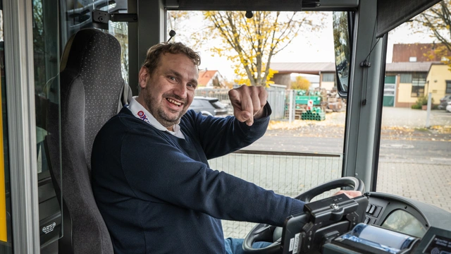 Mann von O.K.-Reisen Kleinhenz lacht am Steuer eines Linienbusses