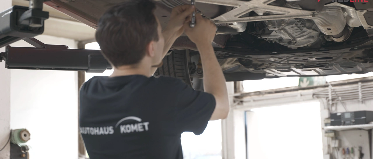Mechaniker des Autohauses Komet arbeitet unter einem Fahrzeug auf der Hebebühne