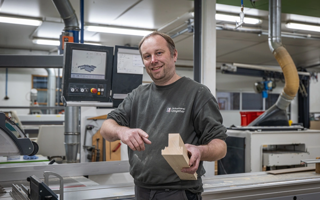 Mitarbeiter an einer CNC-Maschine mit einem fertigen Werkstück
