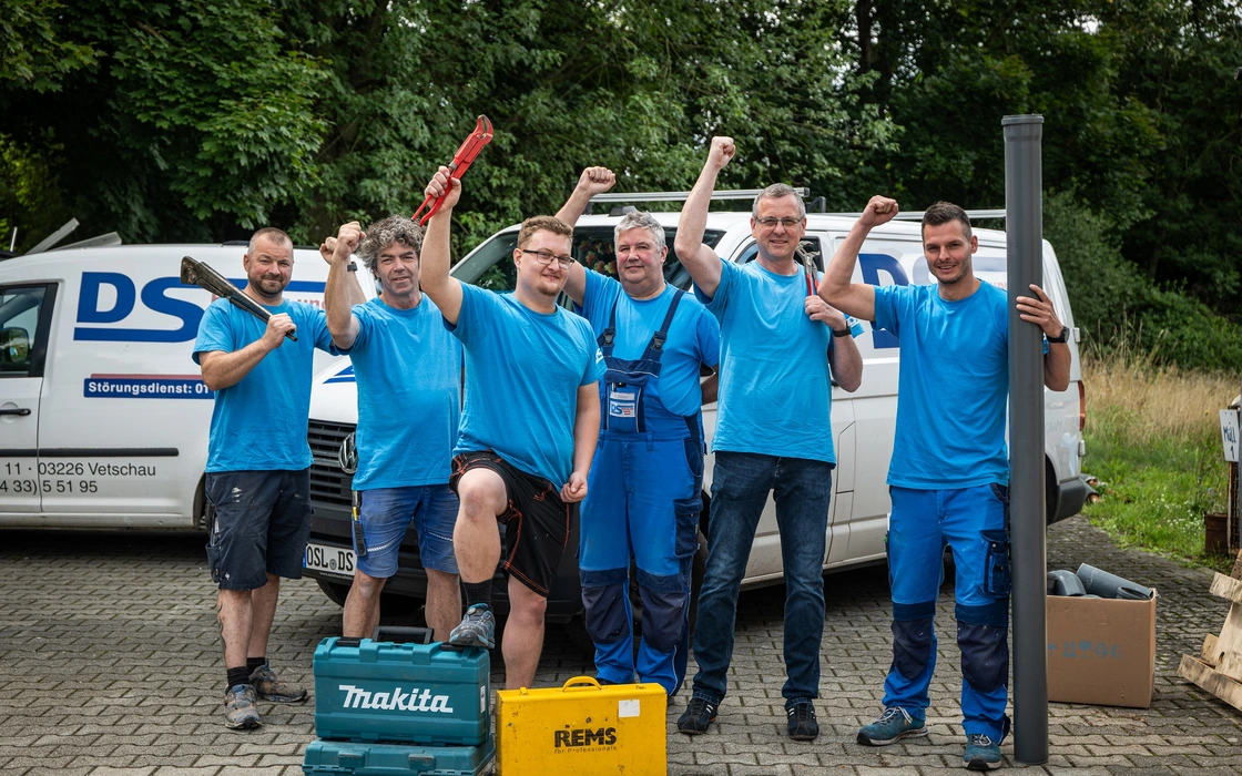 Team eines Heizungs- und Sanitärbetriebs vor seinen Servicewagen