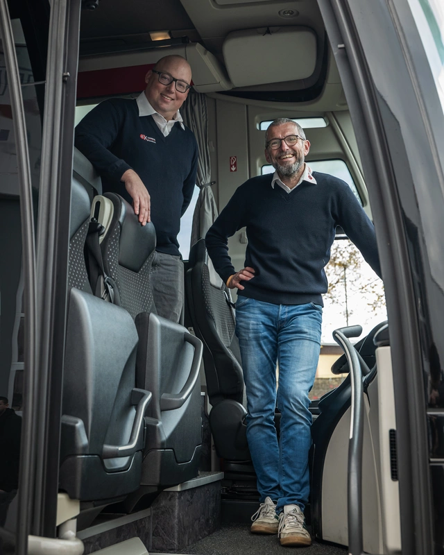 Zwei Männer von O.K.-Reisen Kleinhenz stehen in der Tür eines Reisebusses