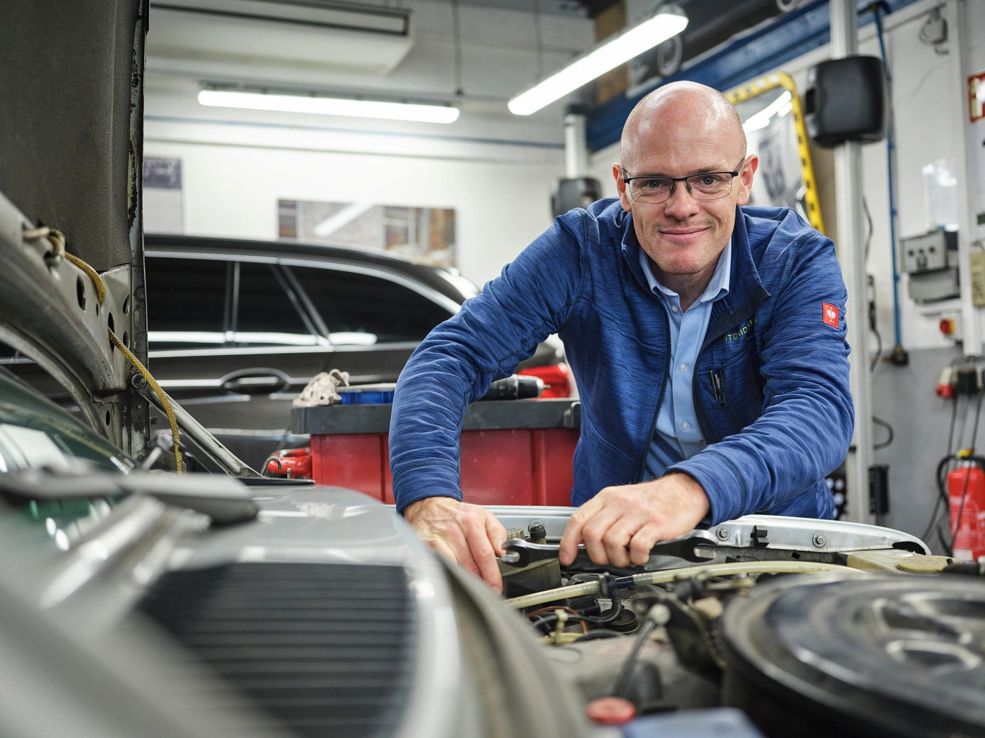 Werkstattleiter am Motorraum eines Fahrzeugs