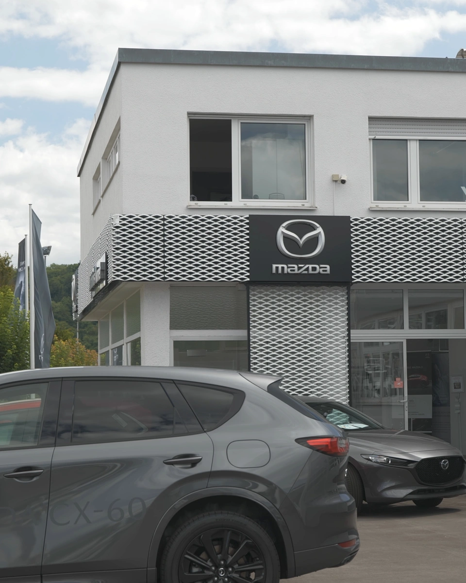 Autohaus Komet mit Mazda-Schild und Neuwagen vor dem Eingang