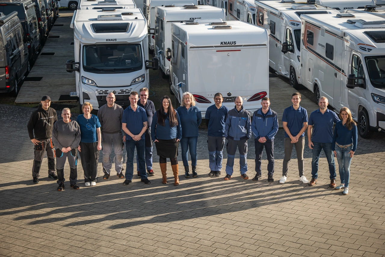 Die ganze Belegschaft eines Caravanhändlers steht in einer Reihe vor den Reisemobilen auf dem Hof