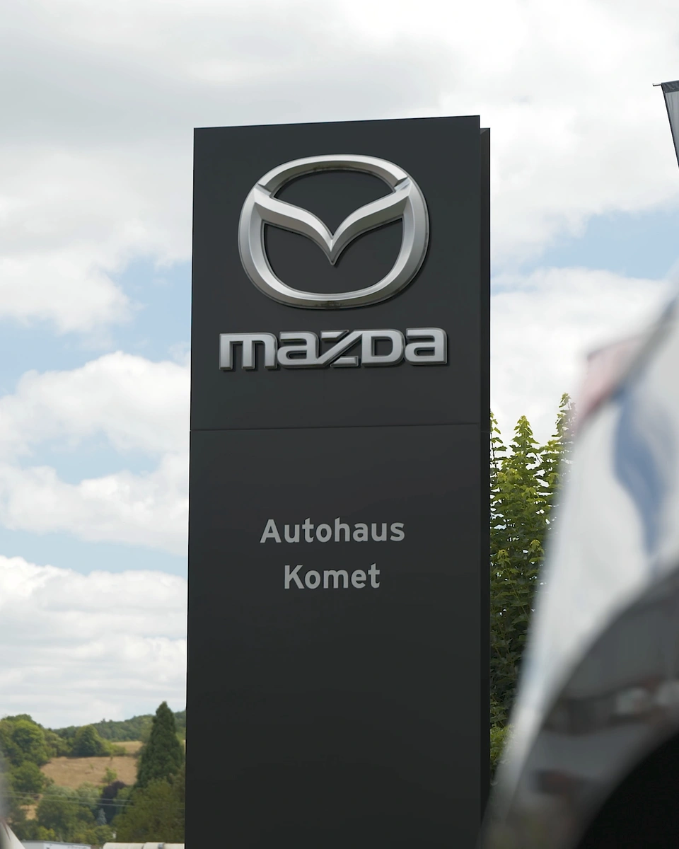 Mazda-Schild mit dem Namen Autohaus Komet vor dem Verkaufsgelände