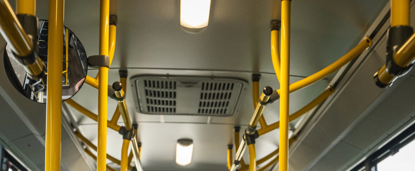 Gelbe Haltestangen und Deckenleuchten im Innenraum eines Linienbusses