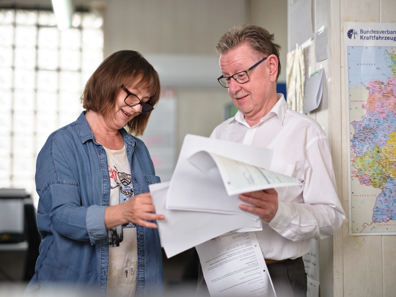 Eine Frau und ein Mann gehen im Büro gemeinsam Unterlagen durch