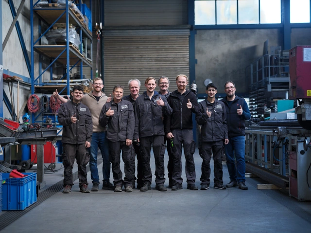Die Mannschaft von metallbau Heimsch steht in der Werkhalle zwischen Maschinen und Materialregalen